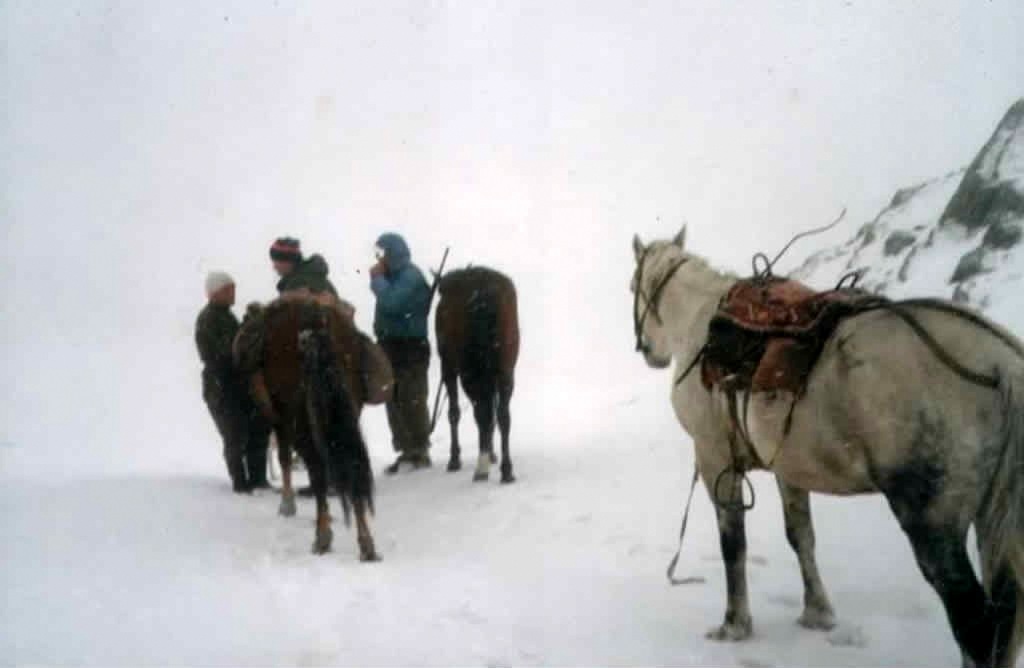 Group of horse traders standing in snow on a mountain pass in the Caucasus